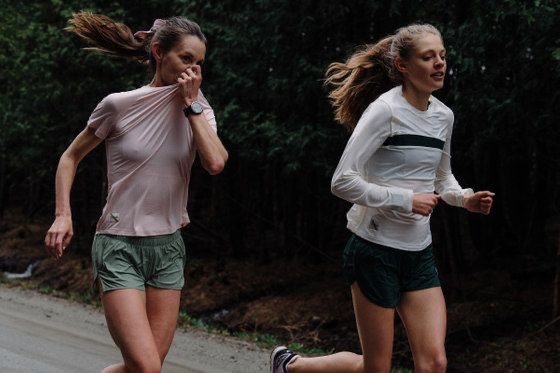 two women running down the road while talking on their cell phones