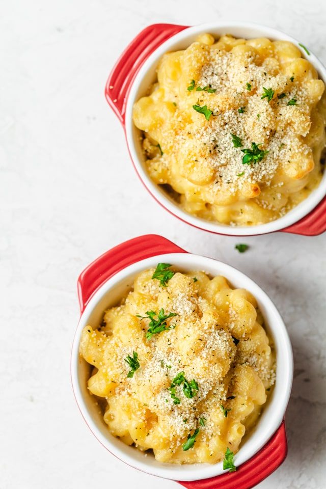 two red bowls filled with macaroni and cheese on top of a white table