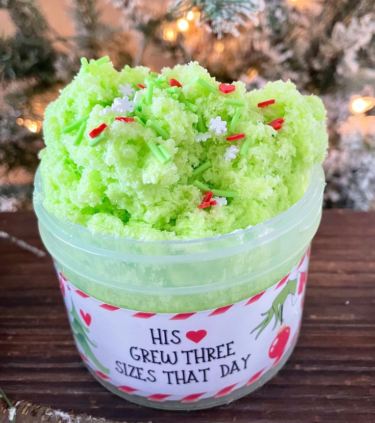 a small plastic container filled with green frosted cake next to a christmas ornament