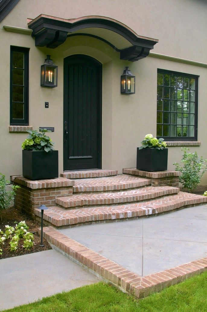 a house with steps leading up to the front door and flowers in planters on either side