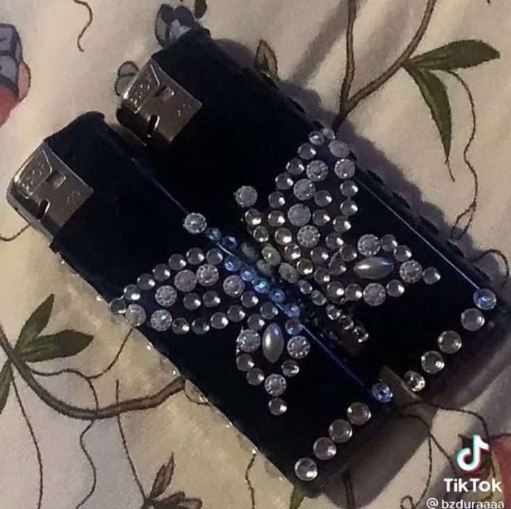 a black purse with lots of silver beads on it sitting on a flowered cloth