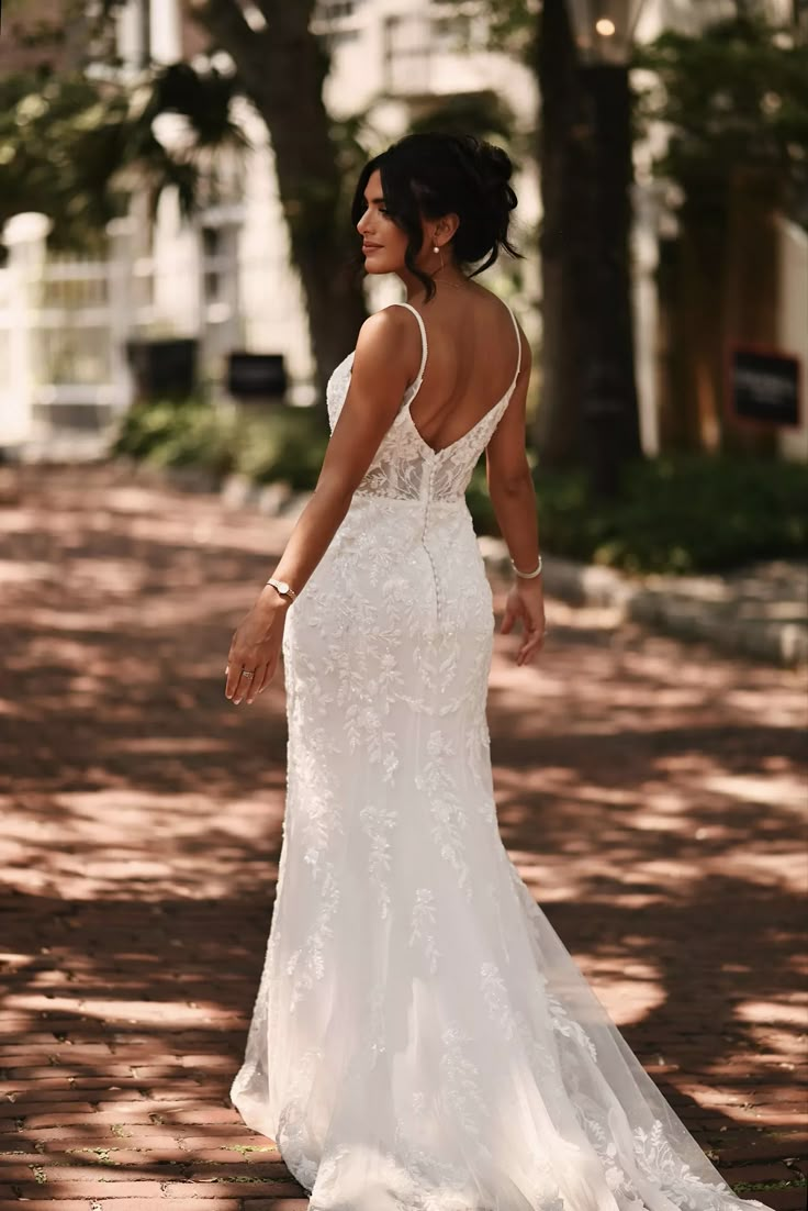 a woman in a white wedding dress is walking down the street with her back to the camera