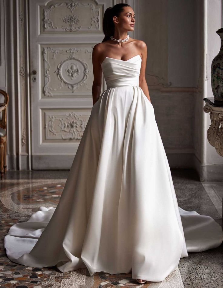 a woman in a white wedding dress standing on the floor