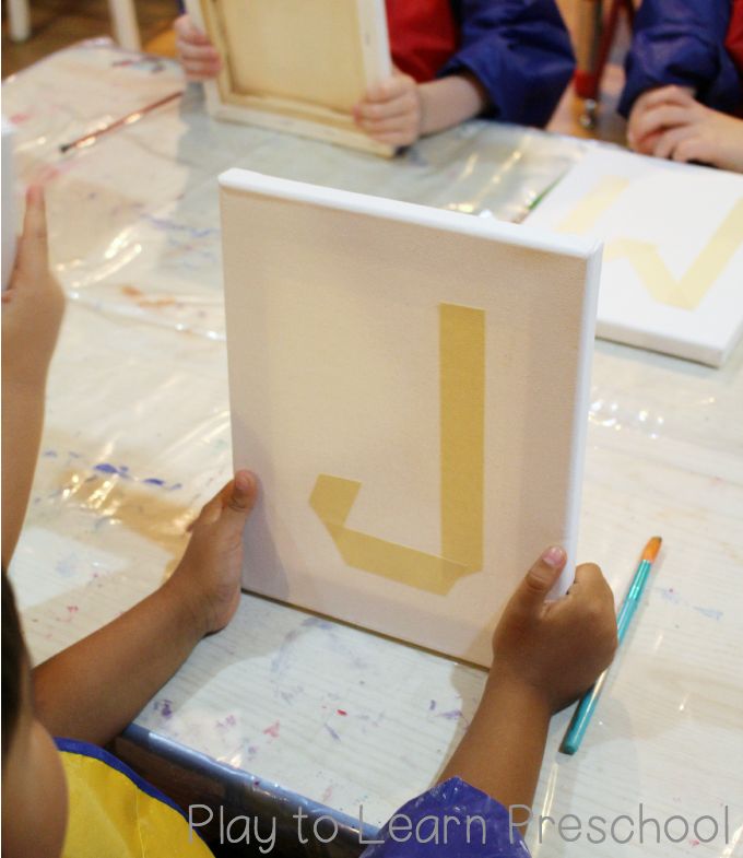 two children are sitting at a table and one child is holding up a sign with the letter l on it