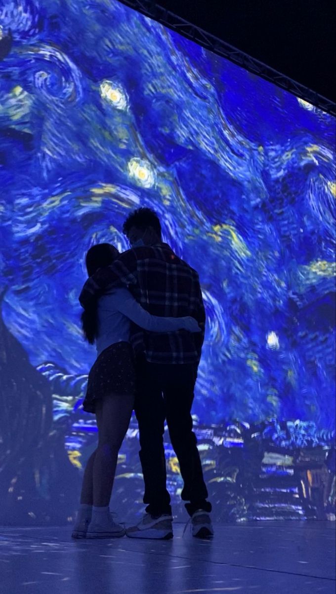 a man and woman hugging in front of a starry sky painting on the wall