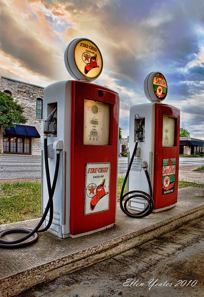 two old fashioned gas pumps sitting next to each other on the side of a road