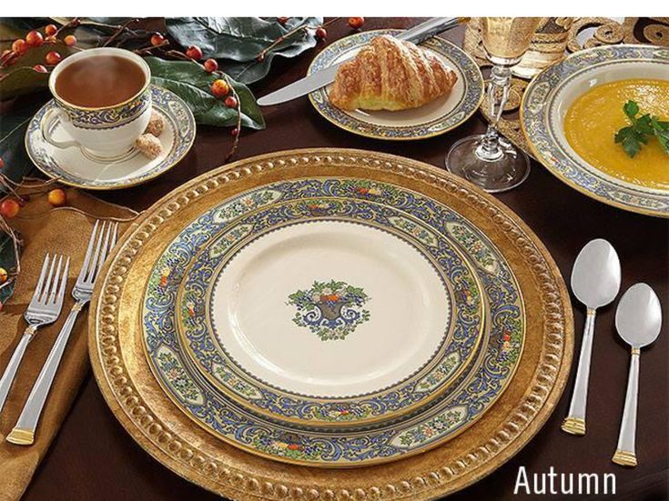 an image of a table setting with silverware and gold rimmed plates on it