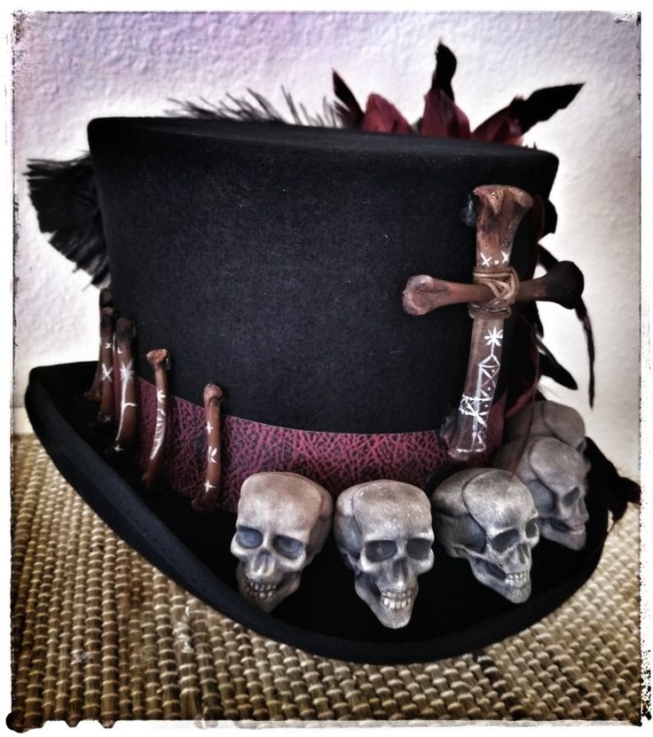 a top hat with skulls on it and a cross hanging from the side, sitting on a table