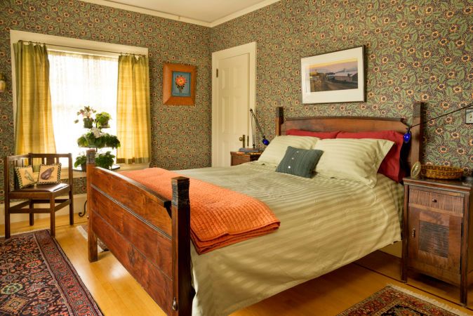 a large bed sitting in a bedroom on top of a hard wood floor next to a window