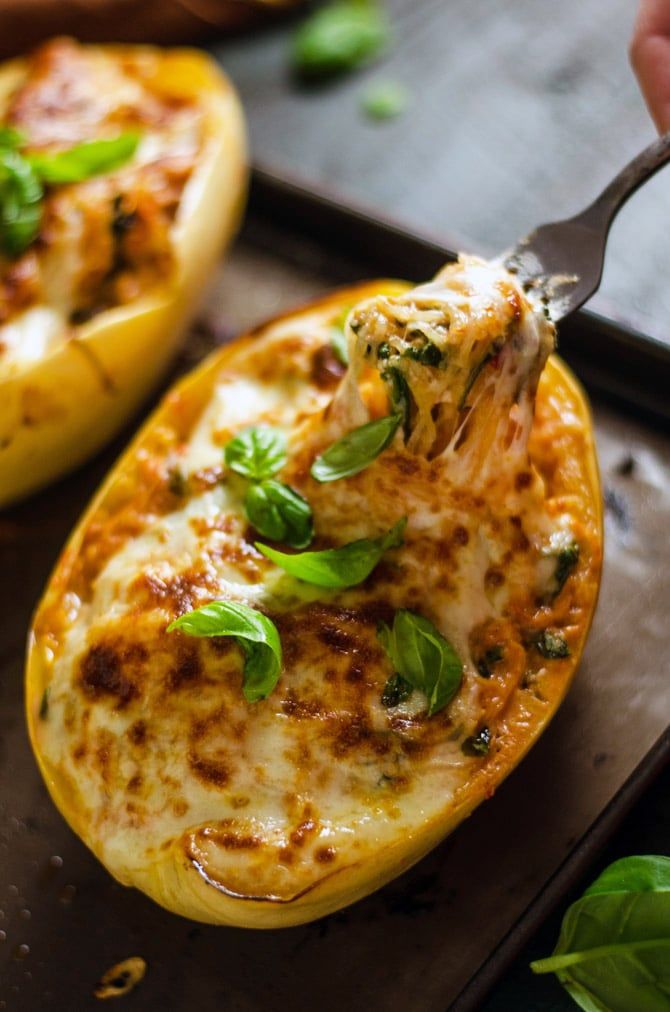 someone is cutting into a stuffed bell peppers with cheese and spinach on the side