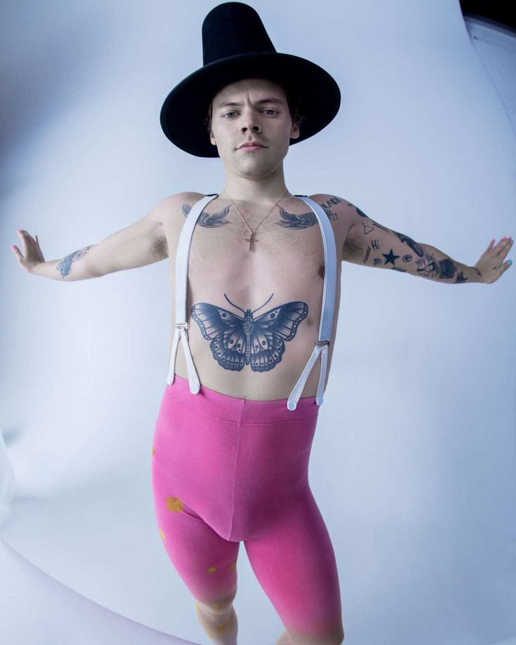 a man with tattoos on his chest wearing pink shorts and a black hat