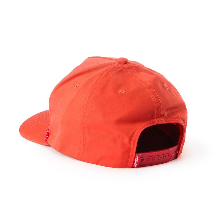 an orange hat with a red patch on the front, and a black strap around the peak