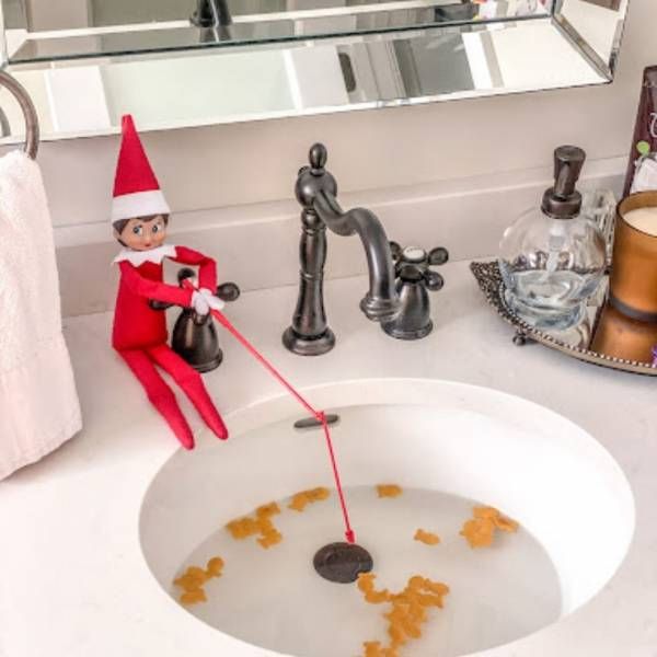 an elf is washing his hands in the bathroom sink with soap and orange peels