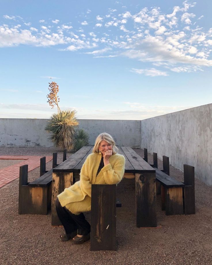 a woman sitting at a wooden table in the middle of an empty area with no one around her