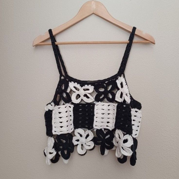 a black and white crocheted top hanging on a wooden hanger