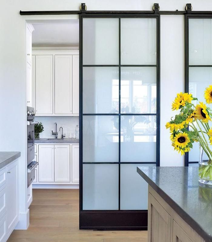 a vase with sunflowers in it sitting on a kitchen counter next to a sliding glass door