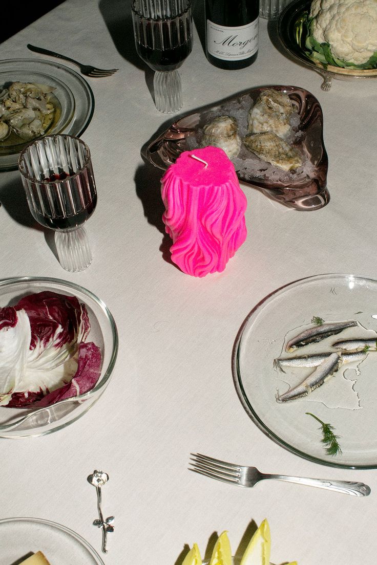 a table topped with plates and silverware covered in food next to bottles of wine