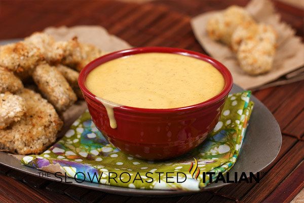 a red bowl filled with sauce next to some fried chicken nuggies on a plate