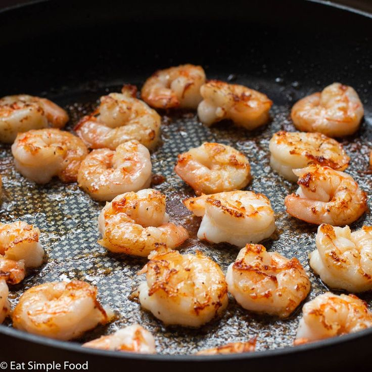 shrimp being cooked in a frying pan with seasonings on the top and bottom