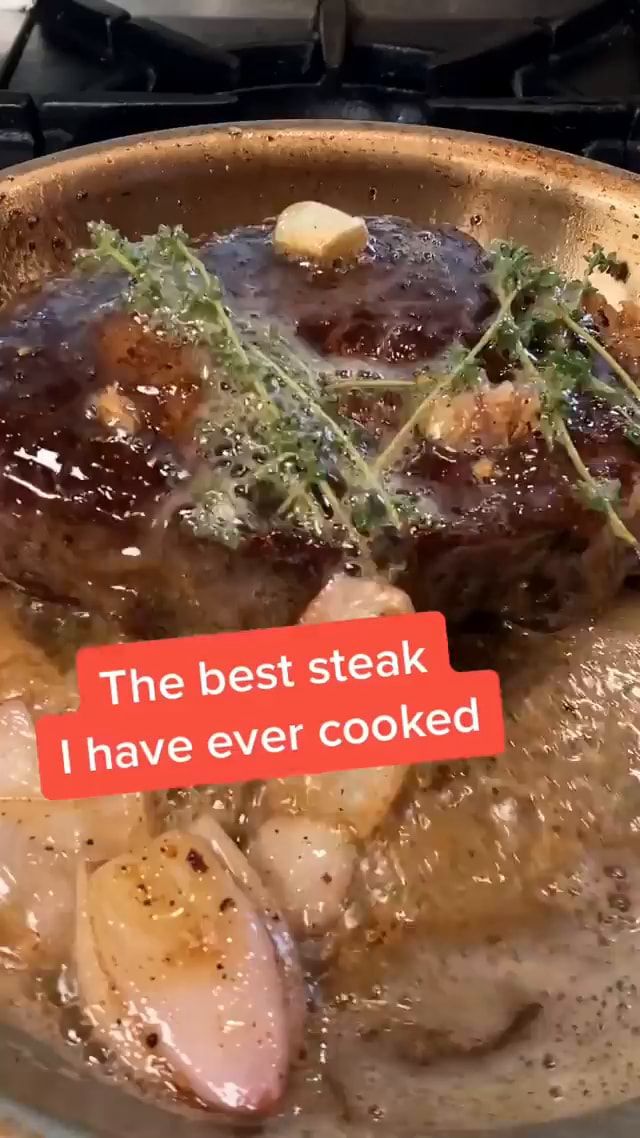 a pan filled with meat and potatoes on top of a stove next to a red sign that says the best steak i have ever cooked