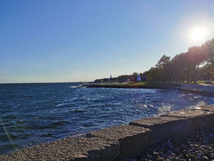 the sun shines brightly over the water and shore