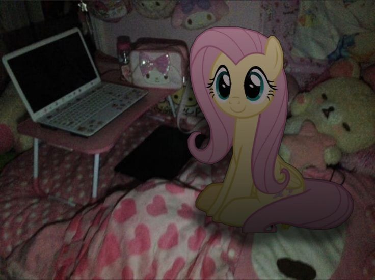 a pink pony sitting on top of a bed next to a laptop computer