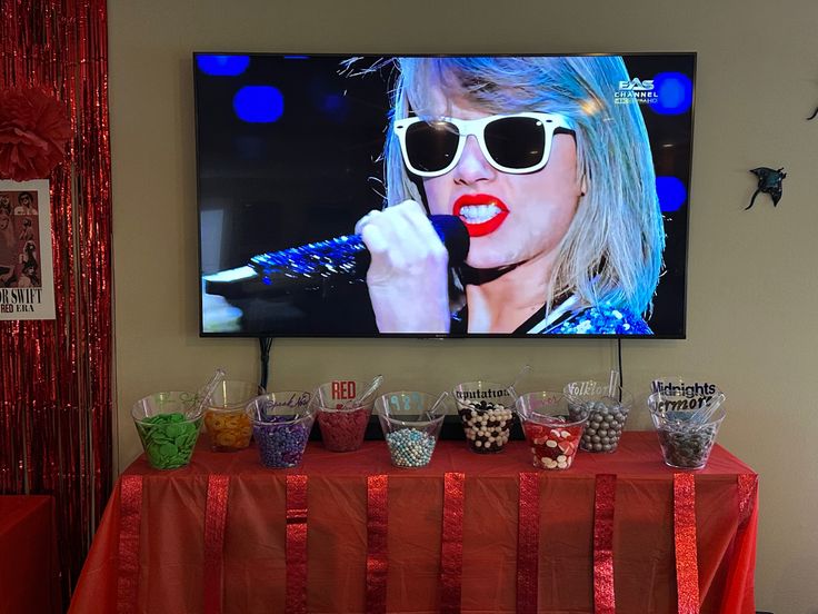 a large screen television mounted to the side of a wall above a buffet table covered in candy