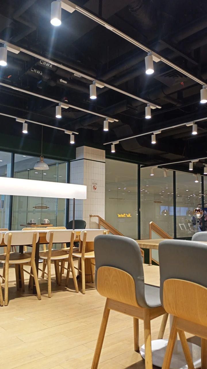 an empty restaurant with wooden tables and chairs in front of glass walls that have lights on them