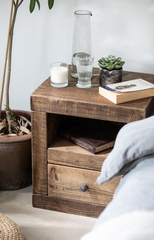 a table with a book, glass and candle on it next to a plant in a pot