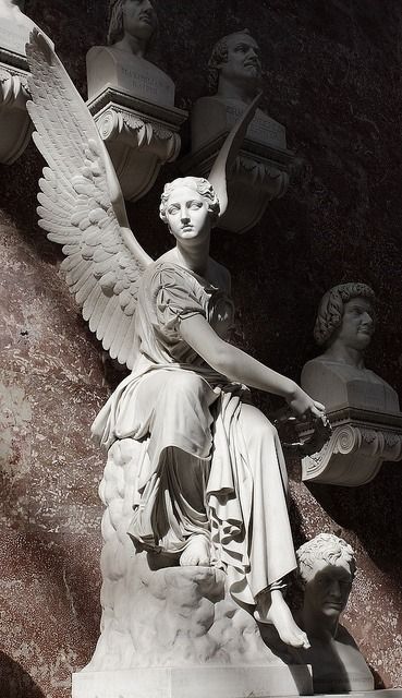 an angel statue sitting on top of a white pedestal