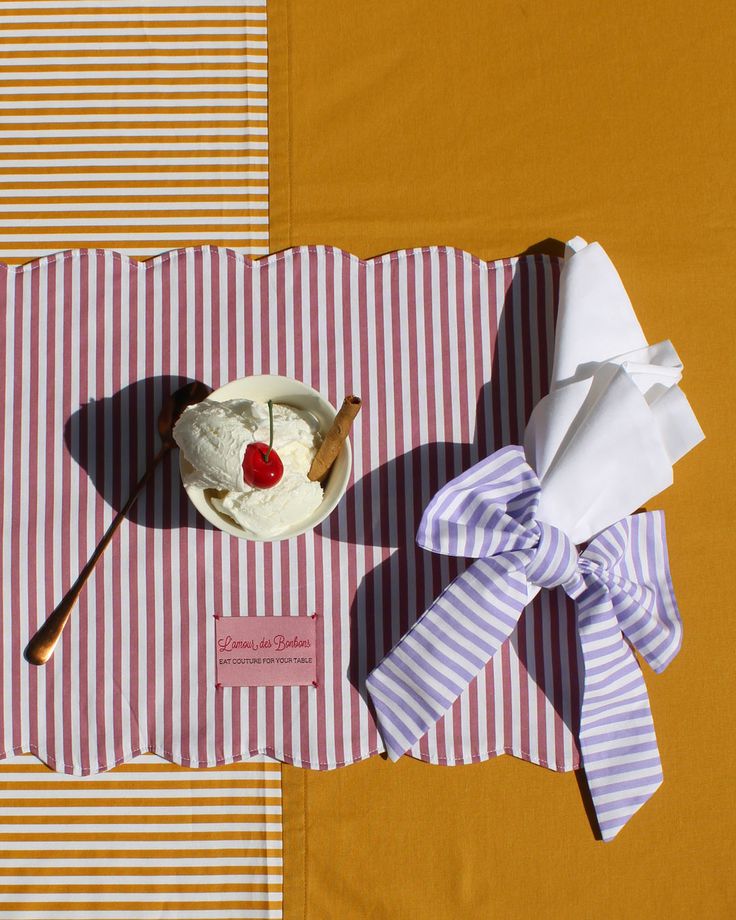 a table topped with a plate of food next to a knife and fork on top of a striped cloth