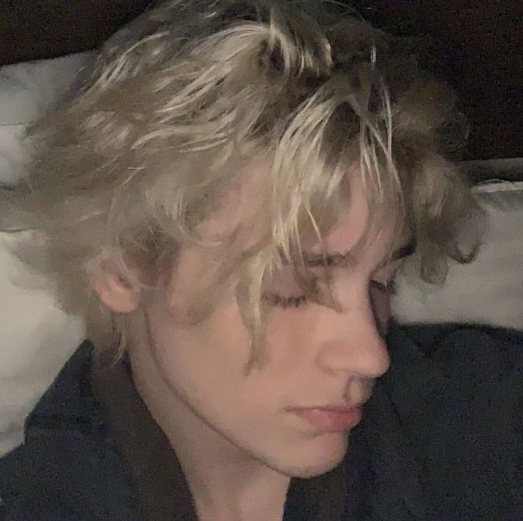 a man with blonde hair laying in bed