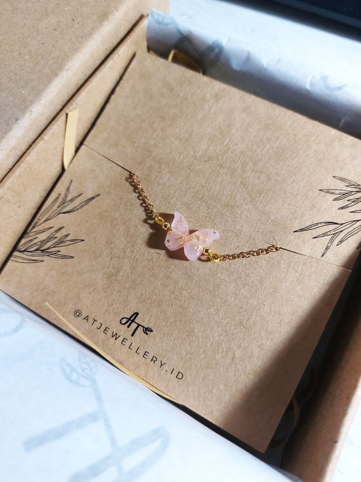 a box with a necklace in it and some flowers on the inside, sitting on a table