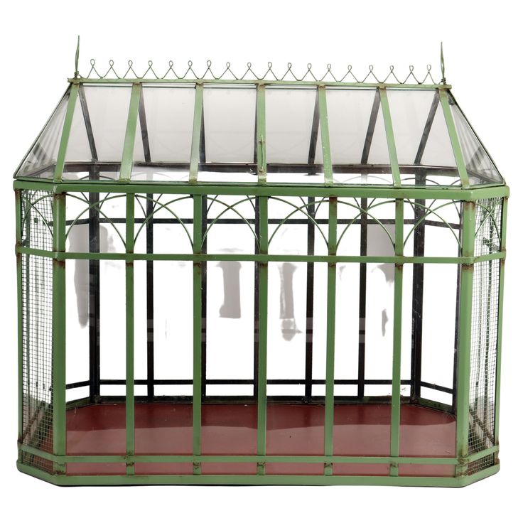 a green metal and glass greenhouse with red flooring on the side, isolated against a white background