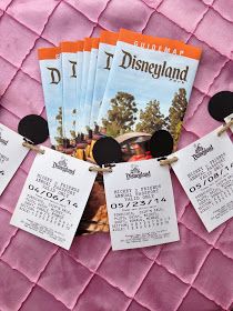 several tickets are hanging on a pink quilted surface with mickey mouse ears attached to them