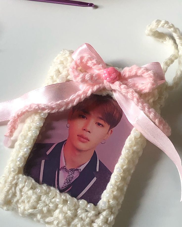 a crocheted photo frame with a pink bow hanging from it's side