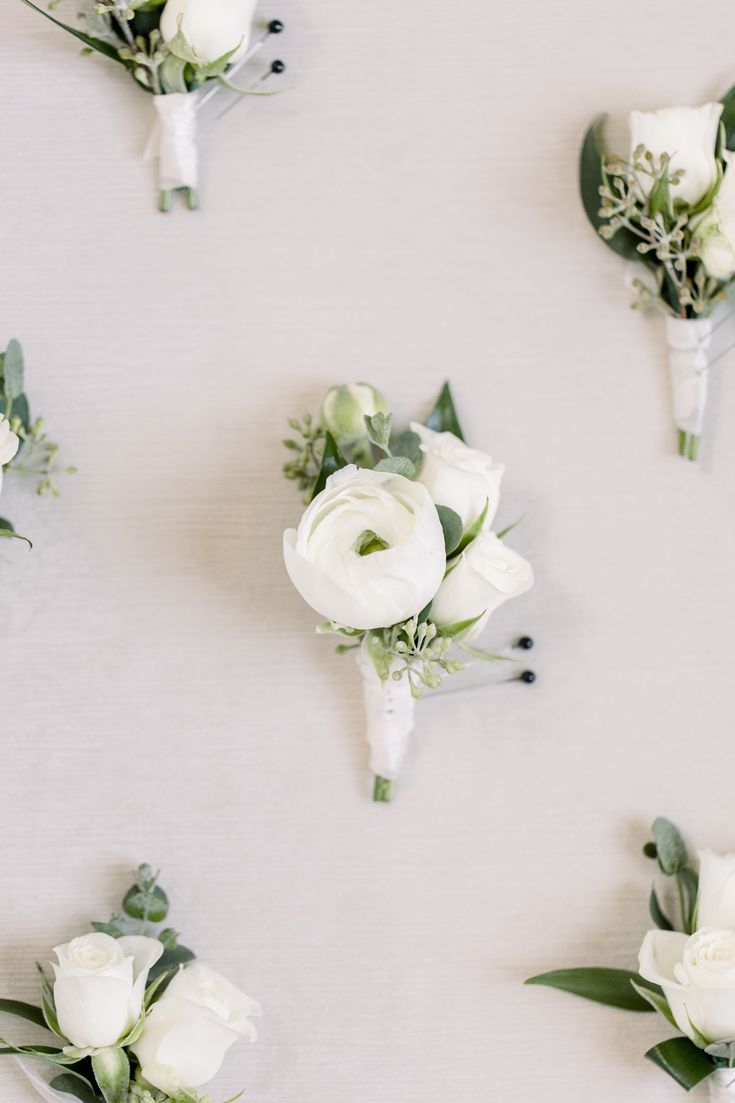 white flowers and greenery are arranged on the wall