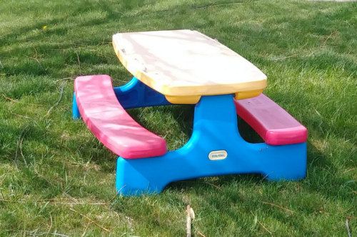 a plastic picnic table sitting in the grass