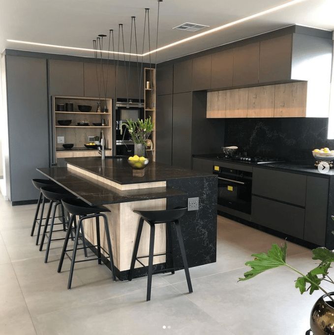 a kitchen with black counter tops and stools next to an island in the middle