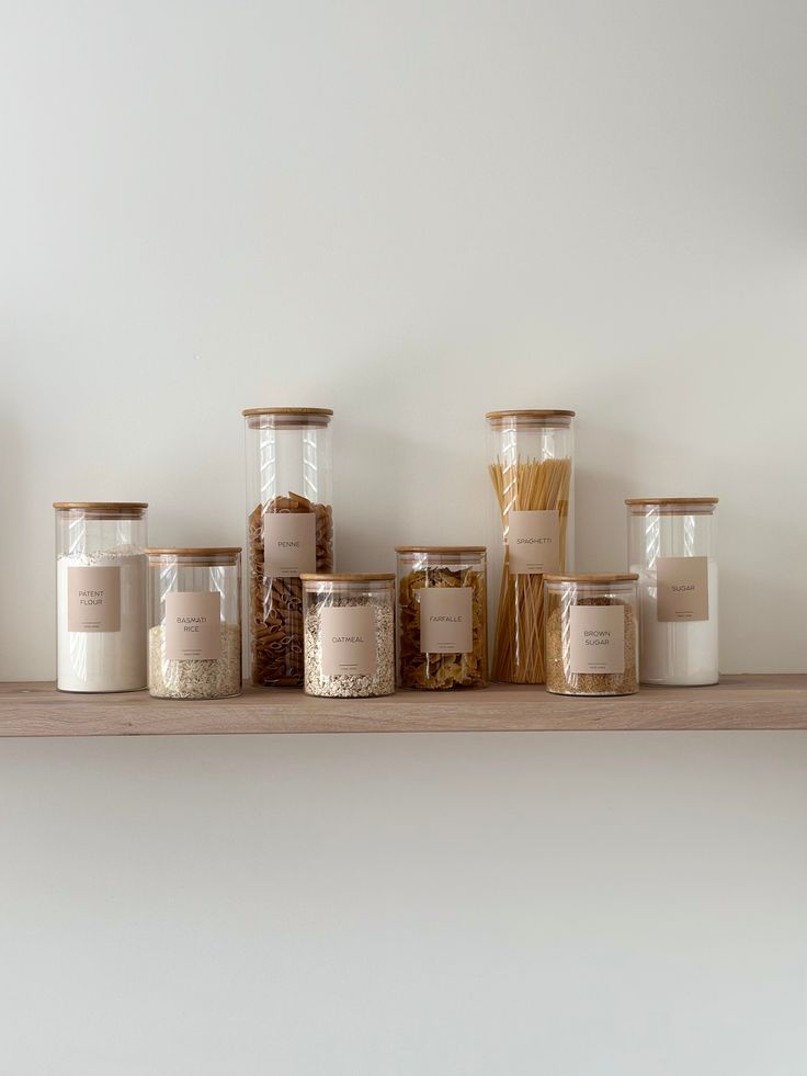 some jars are sitting on a shelf with pasta in them