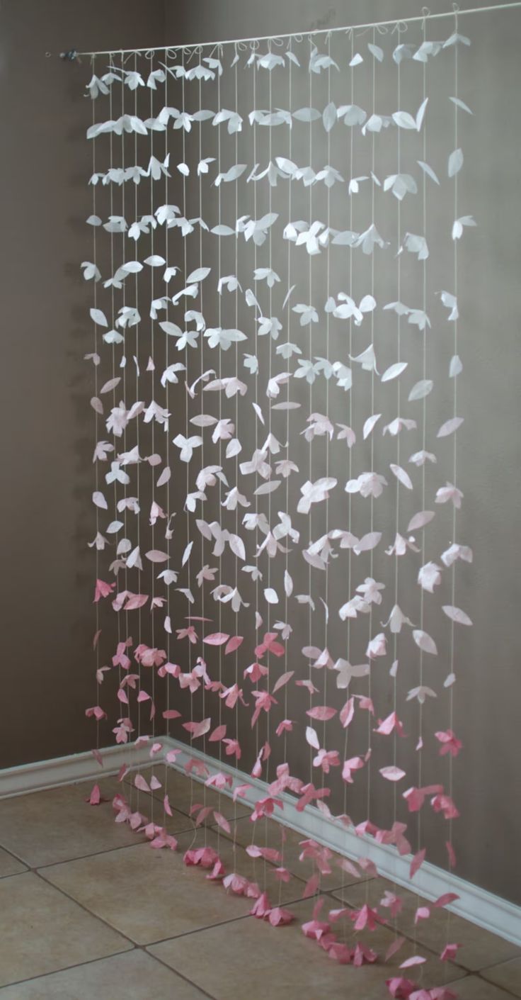 pink and white streamers hanging from the side of a wall next to a tiled floor