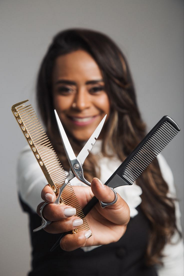 a woman holding two pairs of scissors and comb