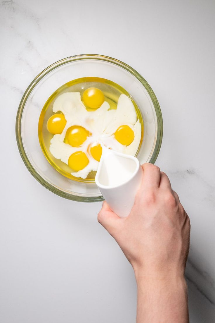 someone is mixing eggs in a glass bowl