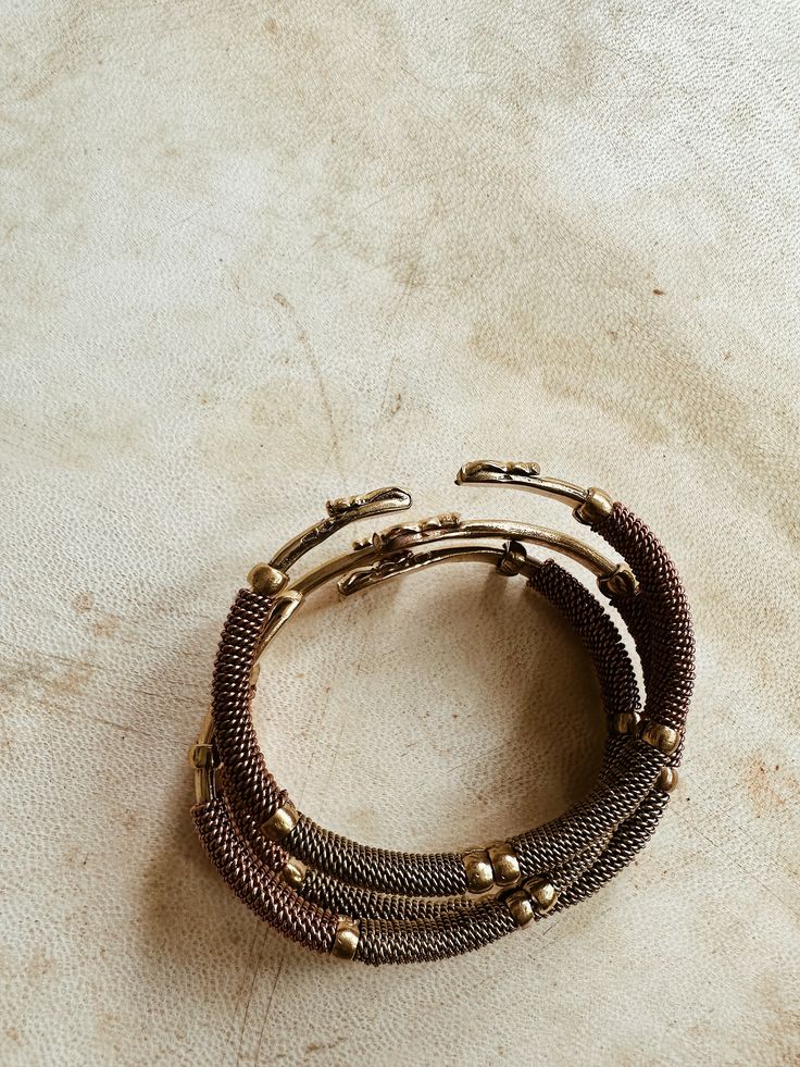 A beautifully handcrafted torque style brass cuff, accented with twisted brass, copper and lightly textured brass beads. Each bracelet is adjustable and can be adjusted to fix smaller or larger wrist. Handmade by African artisans in Kenya. DETAILS: Unisex Metal: Solid Brass & Copper Ships with polishing cloth for everlasting wear. Due to the handmade nature, expect slight imperfections. Each is one of a kind. *Packaged for gift giving. *Sold Individually (1 Bracelet). Not a set. Brown Metal Bangle Bracelet, Adjustable Bronze Copper Bangle, Bohemian Metal Braided Bangle Bracelets, Bohemian Metal Braided Bangle Bracelet, Adjustable Bracelet With Antique Finish, Brown Metal Beaded Bracelets, Unique Adjustable Bracelets With Antique Finish, Unique Adjustable Bracelet With Antique Finish, Bohemian Brown Metal Beaded Bracelets