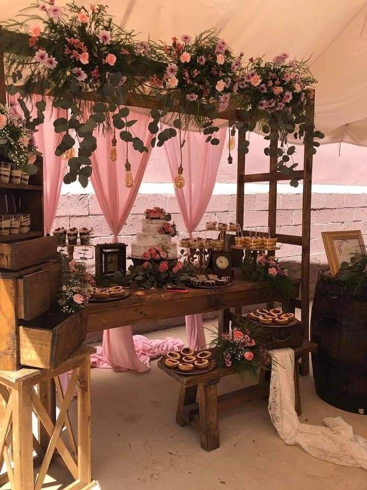 a table with flowers and desserts under a tent on the beach in front of water