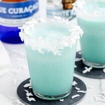 two glasses filled with blue liquid on top of a table