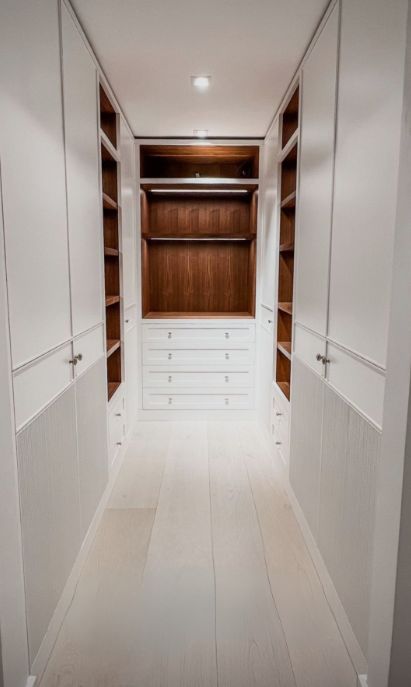 an empty walk in closet with white walls and wood flooring, along with built - in shelving