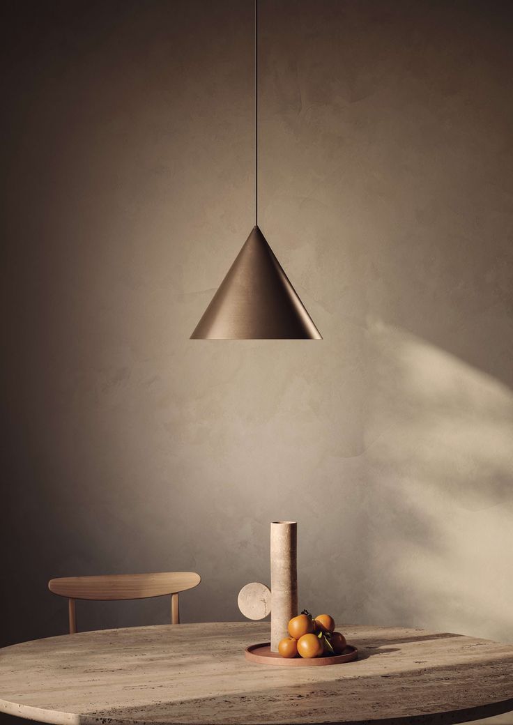 a wooden table topped with oranges and a metal light hanging from the ceiling over it