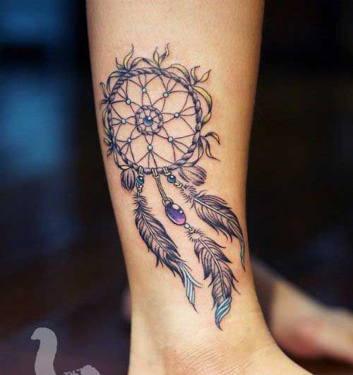 a woman's leg with a tattoo on it that has a dream catcher design