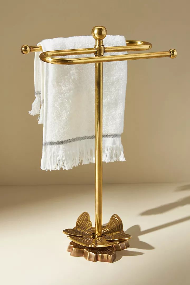 a gold towel rack with two white towels hanging from it